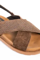 Sandalias de cuero color marrón con tiras cruzadas en el empeine, suela chunky texturizada y tira trasera ajustable con hebilla metálica.