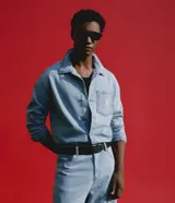 Camisa masculina Blue Steel de corte boxy y silueta amplia, confeccionada en denim de algodón con textura. Presenta cuello camisero clásico, mangas largas, cierre frontal con botones y un bolsillo aplicado en el pecho con detalle de etiqueta.
