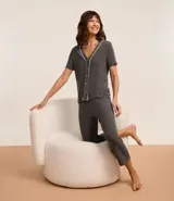 Conjunto de pijama gris oscuro confeccionado en viscosa, compuesto por una camisa de manga corta con cuello en V, abotonada adelante y detalle contrastante blanco; y un pantalón capri con cintura elástica.