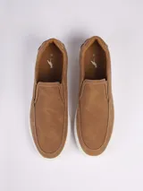 Zapatilla tipo slip-on color marrón, con textura microperforada en la parte superior y suela de goma blanca. Presenta costuras decorativas a la vista.