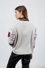 Sweater tejido en lana con viscosa y poliéster, color gris claro, con diseño de estrella roja en el pecho y parches negros en los codos.