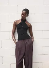 Top negro sin mangas con cuello halter cruzado y diseño entallado al cuerpo.