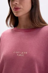 Buzo oversize color bordó con cuello redondo, mangas largas y puños y dobladillo acanalados. Estampado frontal con la frase "C'EST LA VIE PARIS" en color dorado.