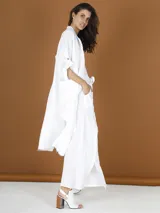 Pantalón blanco de lino de corte palazzo con aberturas laterales y terminaciones desflecadas.