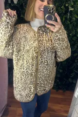 Campera acolchada de corte recto con estampado animal print en tonos neutros. Presenta cierre frontal con botones, cuello redondo y ribetes en color contrastante.