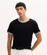 Remera de corte regular confeccionada en tejido texturizado de algodón y poliéster. Presenta cuello redondo y bordes de mangas con detalle de rayas contrastantes en blanco y gris.