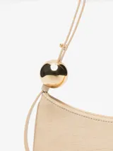 Bolso tipo baguette Jacquemus modelo Le Bisou Perle, de cuero con efecto cocodrilo en color beige. Presenta una correa delgada ajustable con dos esferas metálicas doradas decorativas y el logotipo de la marca en letras doradas en el frente.
