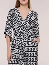 Enterito de calce relajado con caída fluida, escote en V cruzado estilo wrap, mangas tres cuartos estilo kimono y pantalón wide leg. Cuenta con cinto textil a tono para anudar en la cintura y bolsillos laterales, con diseño estampado geométrico en blanco y negro.