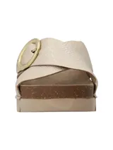 Sandalia de plataforma baja Halifax con tiras cruzadas de cuero sintético en color dorado, suela de corcho y base dentada. Incluye una hebilla metálica circular decorativa en el lateral.