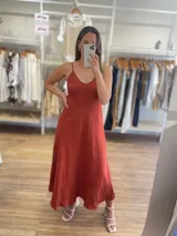 Vestido largo confeccionado en 100% lino de color naranja tierra, con escote en V y tirantes finos. Presenta un diseño fluido y minimalista ideal para la temporada de verano.