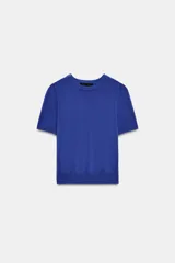 Jersey de punto color azul, con cuello redondo, manga corta y detalle de botones dorados en el hombro.
