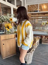 Sweater de lana color crema con rayas verticales anchas color amarillo mostaza, de corte holgado y cuello redondo. Tejido a mano.