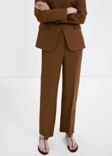 Pantalón marrón de lino, corte recto de tiro medio, con bolsillos laterales y traseros de ribete, trabillas y cierre oculto.