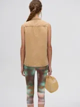 Camisa sin mangas de denim ligero, color celeste lavado, con cuello camisero y botones frontales. Presenta bordados temáticos de playa/mar en el pecho, incluyendo sol, olas, gaviotas, peces y corales/vegetación marina.