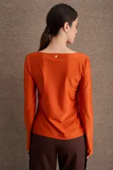Remera de manga larga en color azul, con cuello bote y diseño ajustado al cuerpo. Presenta un acabado de borde sin costuras en el cuello y puños con abertura lateral.