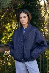 Campera acolchada de color azul marino, con diseño de rombos, cuello tipo chal y cierre frontal con botones grandes al tono. Presenta puños y ruedo acanalados, y bolsillos laterales.