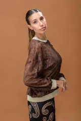 Campera tipo bomber confeccionada en encaje color marrón, con cierre frontal completo y detalles en color crema con destellos dorados en cuello, puños y ruedo.