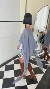 Vestido corto de dos piezas compuesto por una base strapless con frunces y acabado satinado, acompañada de una capa transparente desmontable de corte asimétrico.