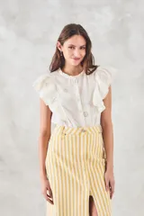 Blusa sin mangas color crema con bordado floral, cuello mao y volados en los hombros.