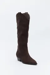 Bota texana de caña alta confeccionada en gamuza negra, con diseño de estilo western, costuras decorativas, tirador superior y taco bajo levemente inclinado.