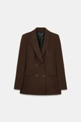 Blazer cruzada color marrón oscuro con cuello solapa, manga larga con hombreras y bolsillos delanteros con solapa. Cierre frontal con cuatro botones.