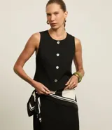 Chaleco negro de corte sastrero, con cuello redondo y botones metálicos.