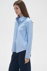 Camisa de algodón blanca, de corte entallado al cuerpo, con cuello camisero, manga larga y cierre frontal de botones.