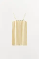 Vestido mini de corte recto en color amarillo suave, con tirantes anchos, escote recto con detalles de encaje a tono y un delicado lazo frontal.