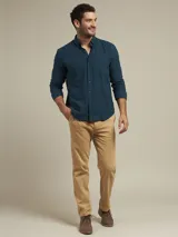 Pantalón de vestir color beige, de corte recto, con bolsillos laterales y traseros. Se ajusta a la cintura con cinturón de cuero marrón.