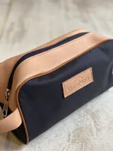 Neceser de lona verde con detalles en cuero color beige y etiqueta con logo de la marca Sierra Mora.