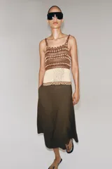 Top de crochet con escote recto y tirantes finos. Presenta un diseño bicolor con la parte superior en color marrón y la parte inferior decorada con abalorios en tonos crema y marrón.