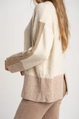 Sweater oversize de lana con diseño color block, combinando un cuerpo en tono crema con motas multicolores y una franja inferior ancha en color visón. Presenta cuello redondo y detalles acanalados en el cuello, puños y ruedo, además de franjas laterales texturizadas en las mangas.