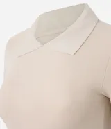 Blusa polo beige de manga corta, confeccionada en tejido canelado de rib de algodón con elastano, que proporciona un ajuste cómodo y una caída ajustada.