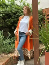 Saco largo color naranja de tejido de punto en algodón, con solapas y bolsillos de cuero marrón.