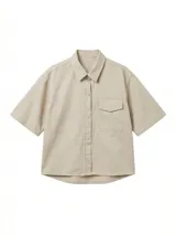 Camisa de manga corta color crudo, confeccionada en gabardina, con cuello camisero y botones frontales. Presenta un bolsillo de parche en el pecho y bordado en la espalda.