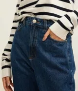 Pantalón mom jeans de tiro alto, color azul denim, con bolsillos delanteros y traseros, trabillas en la cintura y pespuntes contrastantes.