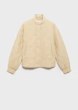 Chaqueta acolchada color crema, estilo bomber, con cuello perkins, cierre frontal con botones, dos bolsillos laterales y detalle fruncido en el bajo.