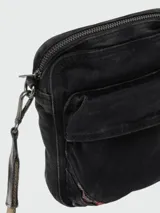 Bandolera Diesel de diseño compacto, confeccionada en denim negro con efecto desgastado. Cuenta con múltiples compartimentos con cierre, correa ajustable y desmontable, y detalle de etiqueta con logo de la marca en el lateral.
