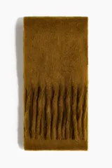 Bufanda de tejido suave con textura afelpada y flecos largos en los extremos. Presenta un pequeño parche con monograma en relieve.