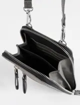 Porta celular de cuero sintético color marrón, con diseño rectangular, cierre principal y dos bolsillos frontales con cierre. Incluye correa larga regulable y extraíble, y cuenta con el logo de la marca grabado en la parte inferior.