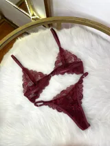 Conjunto de lencería compuesto por corpiño triangular de encaje con cierre frontal y tanga regulable a juego, confeccionado en encaje suave y elastizado.