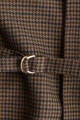 Blazer cruzado con estampado de pata de gallo en tonos marrón y negro. Presenta cuello elevado, hombreras, abertura en los puños, bolsillos delanteros ribeteados y un cinturón fino para ajustar la cintura. Está forrado.