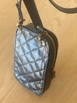 Cartera pequeña negra con diseño acolchado, cierre de cremallera y correa de mano. Incluye tarjetero interno.