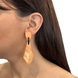 Aros colgantes color salmón con forma geométrica irregular y detalles en negro.