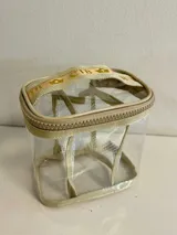 Neceser transparente con bordes y cierre color beige.