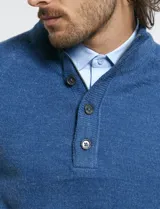 Sweater de punto color azul marino, con cuello alto, cierre frontal parcial y tapeta con botones. Presenta mangas raglán y puños y ruedo acanalados.