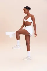 Pollera deportiva color rosa fucsia, con estampado en relieve de texto. Es de corte corto con ruedo redondeado y cuenta con shorts internos.