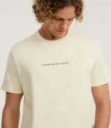 Remera color crema de algodón, corte clásico, con cuello redondo y mangas cortas. Estampa frontal con la frase "Nascido num País Tropical".