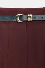 Pantalón de tiro alto y corte tobillero, confeccionado en tejido de aspecto denim oscuro. Presenta diseño de pinzas frontales, bolsillos laterales y cierre frontal con cremallera, botón y gancho. Incluye un cinturón fino a tono con hebilla metálica dorada.
