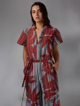 Mono de lino mezcla con estampado vegetal en tonos rojos, grises y blancos, de manga corta, escote en V y piernas amplias con cinto incorporado para ajustar la cintura.